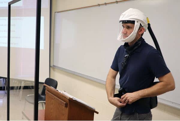 man in white mask in Wescoe Hall classroom